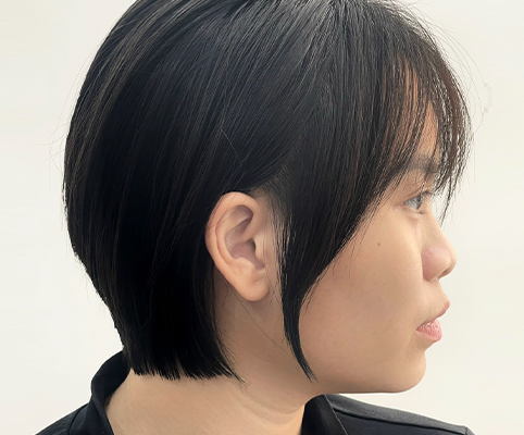 Tóc ngắn đen ôm gáy, mái mỏng và phần tóc mai dài, nhìn nghiêng.